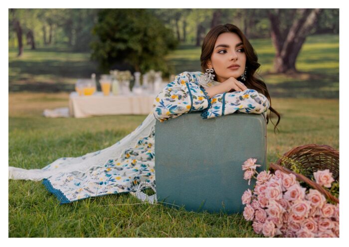 A woman in a floral print dress stands beside a suitcase