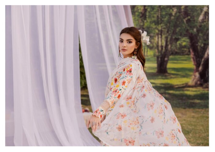 A WOMAN IN A FLORAL DRESS STANDING IN A GARDEN